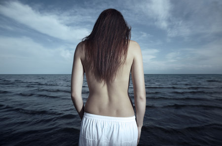 Rear view on the lonely woman sadding at the seaの写真素材