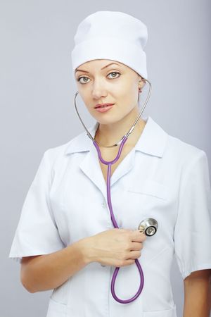 Young female doctor with stethoscope monitoring her heartの写真素材