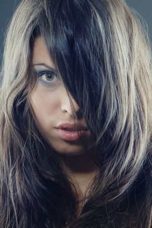 Vertical portrait of the pretty woman with perfect makeup and long hairs covering half of faceの写真素材