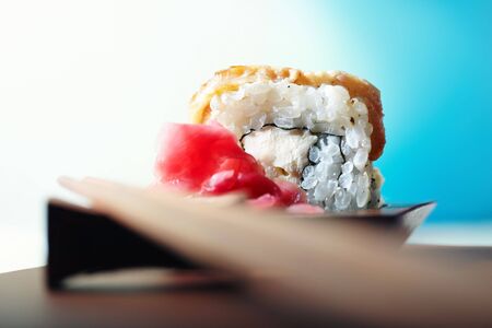 Close-up horizontal photo of the rolled sushi with ginger on the table and chopsticks. Shallow depth of field and vivid colorsの写真素材