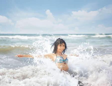 Happy lady playing with water and waves in the summer seaの写真素材