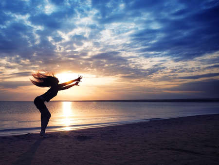 Dancing dynamic woman at the beach during sunsetの写真素材