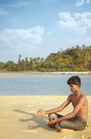 Indian man in cross-legged position at the summer beach doing Yoga meditationの写真素材