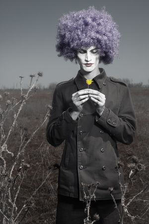 Romantic photo of the clown outdoors holding yellow flowerの写真素材