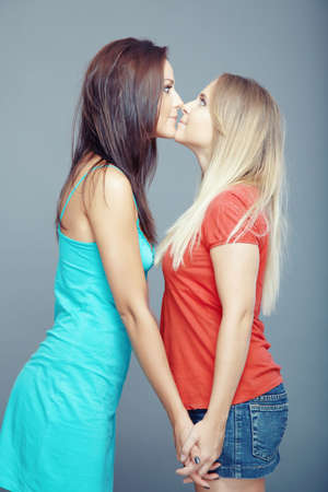 Two young girls looking to the eyes of each other. Vertical studio photoの写真素材