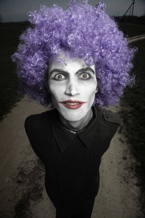 Crazy man outdoors with wig and clown makeup. Artistic darkness and colors addedの写真素材