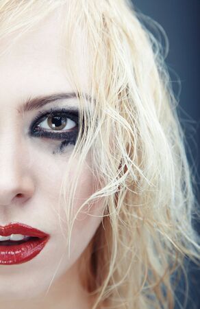Half face of the blond lady with strange grungy makeup. Vertical photo with natural colorsの写真素材