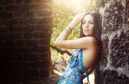 Elegant lady outdoors near the old stony walls. Sunlight at the backgroundの写真素材