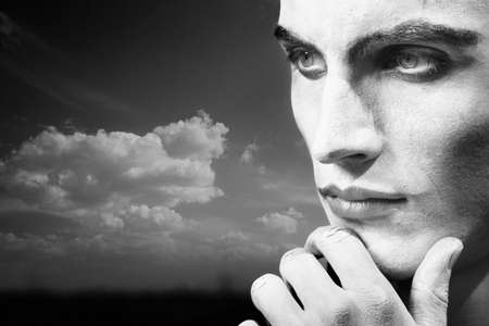 Sad clown outdoors with face-paint. Horizontal headshot. Artistic darkness, texture and noise addedの写真素材