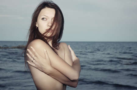 Single lady at the sea with hair blown by the wind. Natural light and colorsの写真素材