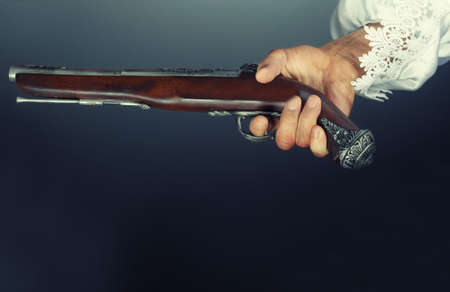 Pirate hand holding ancient pistol. Studio shot. Natural colors and darknessの写真素材
