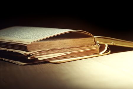 Old damaged book on the table on a dark backgroundの写真素材