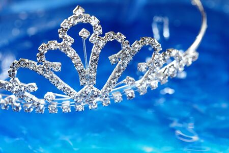 silver diadem with diamonds on a blue water background. Shallow depth of field added by macro lens for natural viewの写真素材