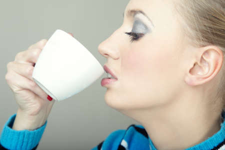 Woman in stiped sweater drinking tea or coffee indoorsの写真素材