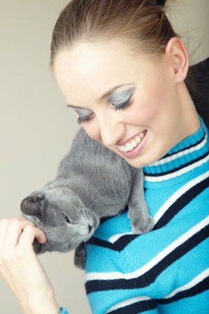 Smiling lady pampering her cat indoors. Natural light and colorsの写真素材