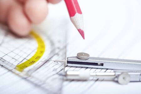 Human hand drawing engineering scheme with red pencil. Close-up photoの写真素材