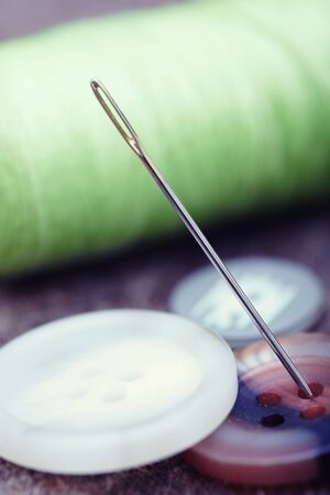 Buttons and sewing needle. Extremely close-up photo with shallow depth of fieldの写真素材