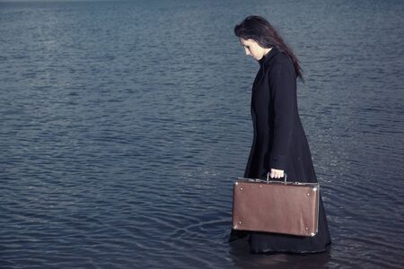 Side view on the lady holding case and going in the seaの写真素材