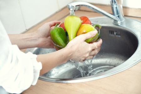 Hands of woman washing vegetables at her kitchenの写真素材