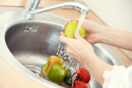 Hands of woman washing vegetables at her kitchenの写真素材
