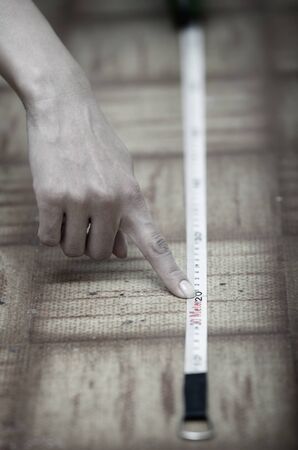 Human hands using measuring tape on a wooden surfaceの写真素材