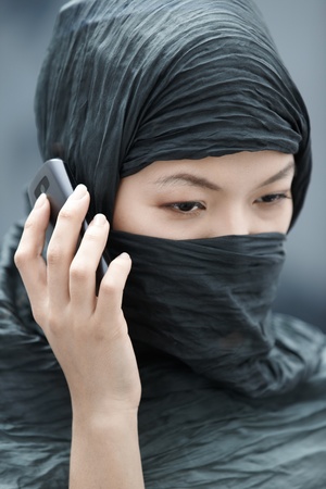 Muslim lady in hijab talking via cell phoneの写真素材