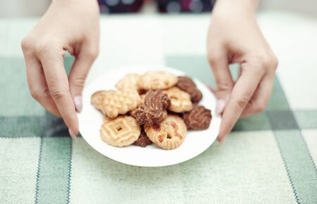 Human hands putting plate with cookies to the tableの写真素材