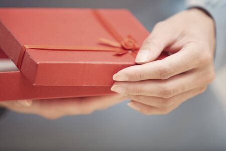 Hands of woman opening red gift box