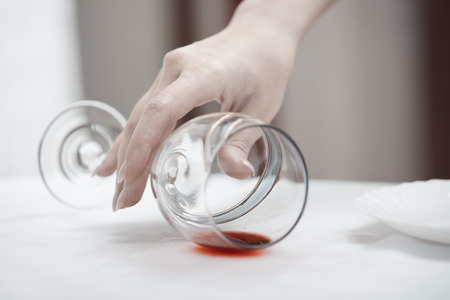 Human hand taking fallen wineglassの写真素材