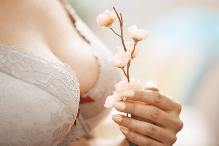 Woman in brassiere holding Sakura flower. Close-up horizontal photoの写真素材