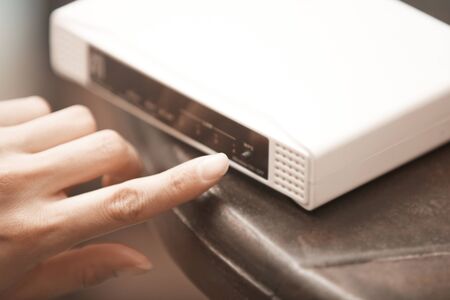 Human hand turning on wireless modem. Close-up horizontal photoの写真素材
