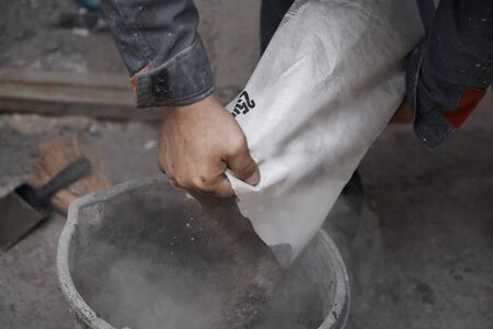Construction worker pouring the cement to the bucketの写真素材