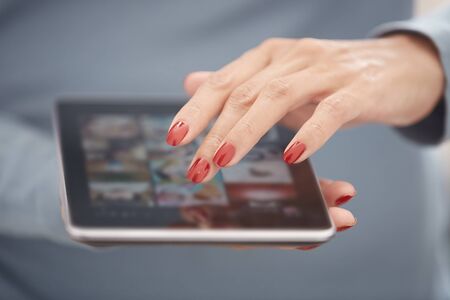 Woman with red manicure using tablet computer. Horizontal photoの写真素材