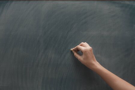 Human hand with chalk at the blackboardの写真素材