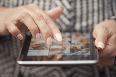 Woman with tablet computer looking digital photosの写真素材