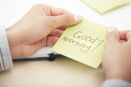 Hands holding sticky note with Good morning text