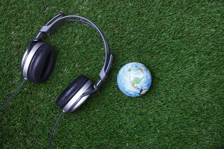 Headphone and earth globe on a grassの写真素材