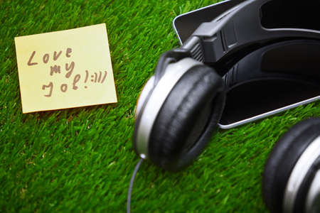 Text on sticky note on a grass with headphones and digital tabletの写真素材