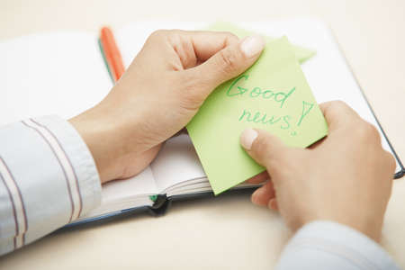 Woman holding sticky note with Good news textの写真素材