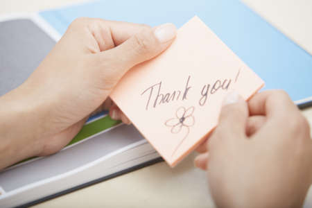Hands of woman holding sticky note with Thanks text