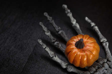 Skeleton hand holding Halloween pumpkinの写真素材