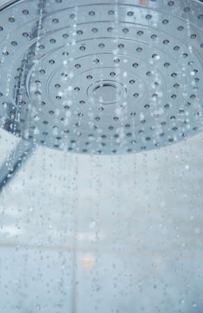 Shower head with flowing water. Close-up vertical photoの写真素材
