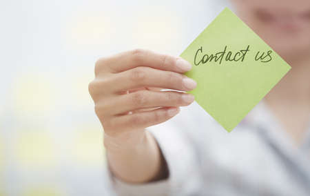 Woman holding sticky note with Contact us textの写真素材