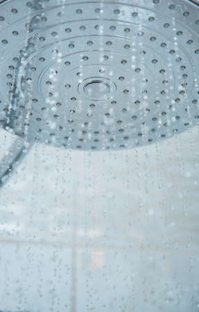 Shower head with flowing water. Close-up vertical photoの写真素材