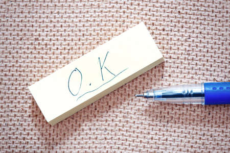 OK sign written on a label and blue penの写真素材