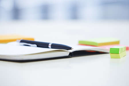 Ballpoint pen on the notepad and adhesive notes in the officeの写真素材