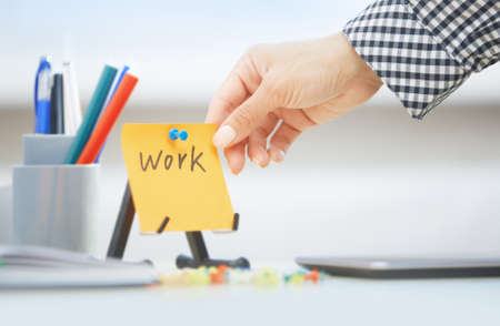 Human hand holding adhesive note with Work textの写真素材