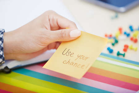 Human hand holding adhesive note with Use your chance textの写真素材