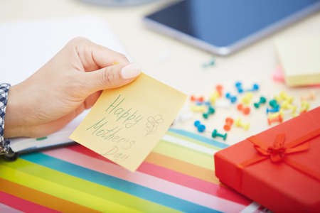 Human hand holding adhesive note with Happy mothers day textの写真素材