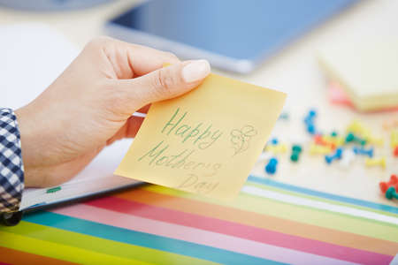 Human hand holding adhesive note with Happy mothers day textの写真素材